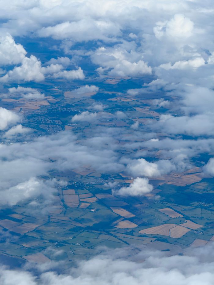 Aerial photograph showcasing agricultural fields partially obscured by clouds.