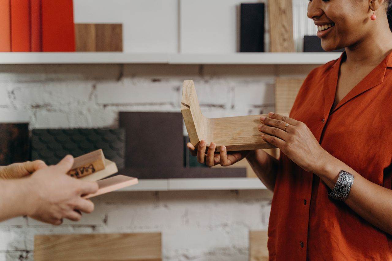 Two adults discussing wooden samples in a modern studio setup, showcasing material design.